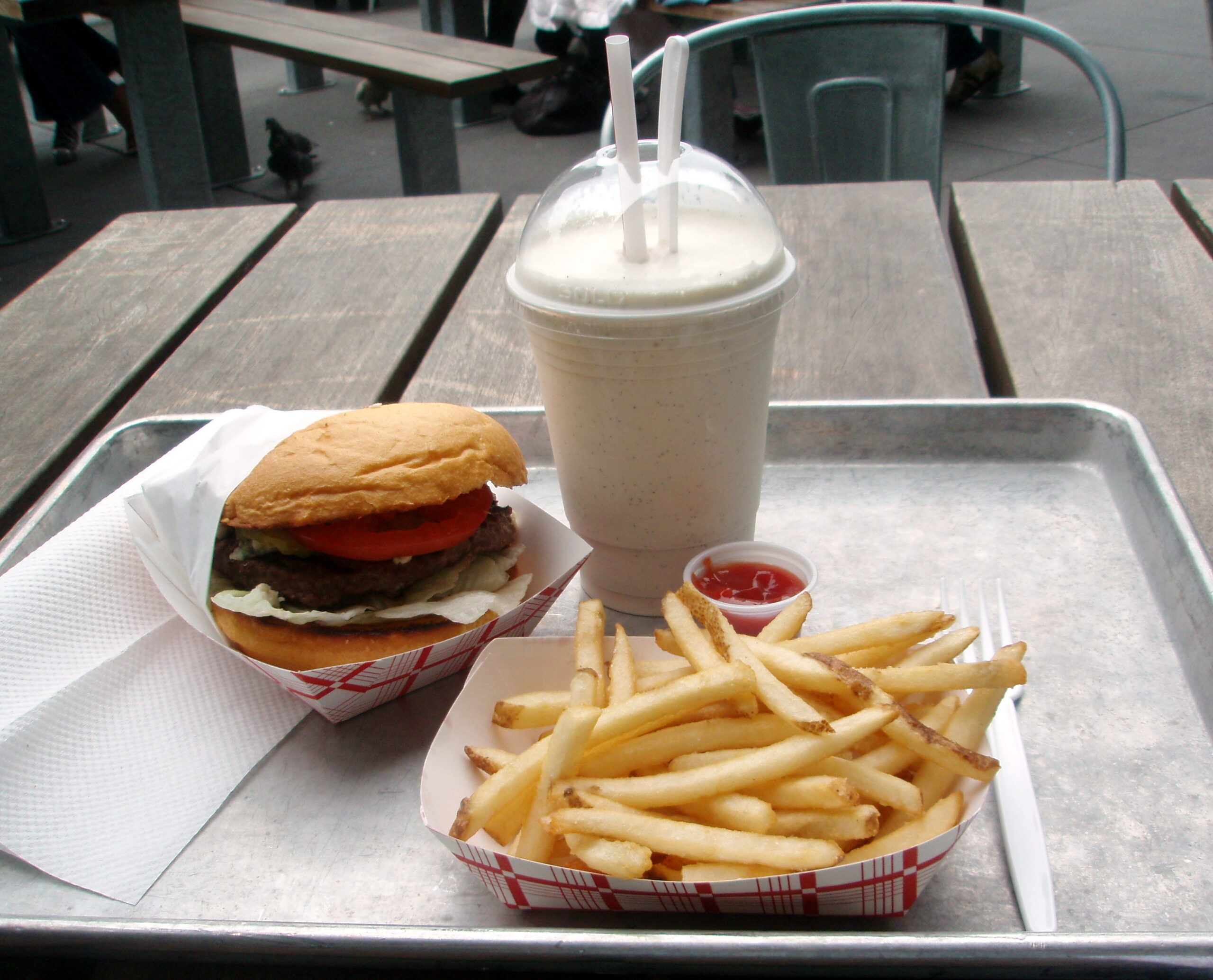 A cheeseburger with fries and a vanilla milkshake