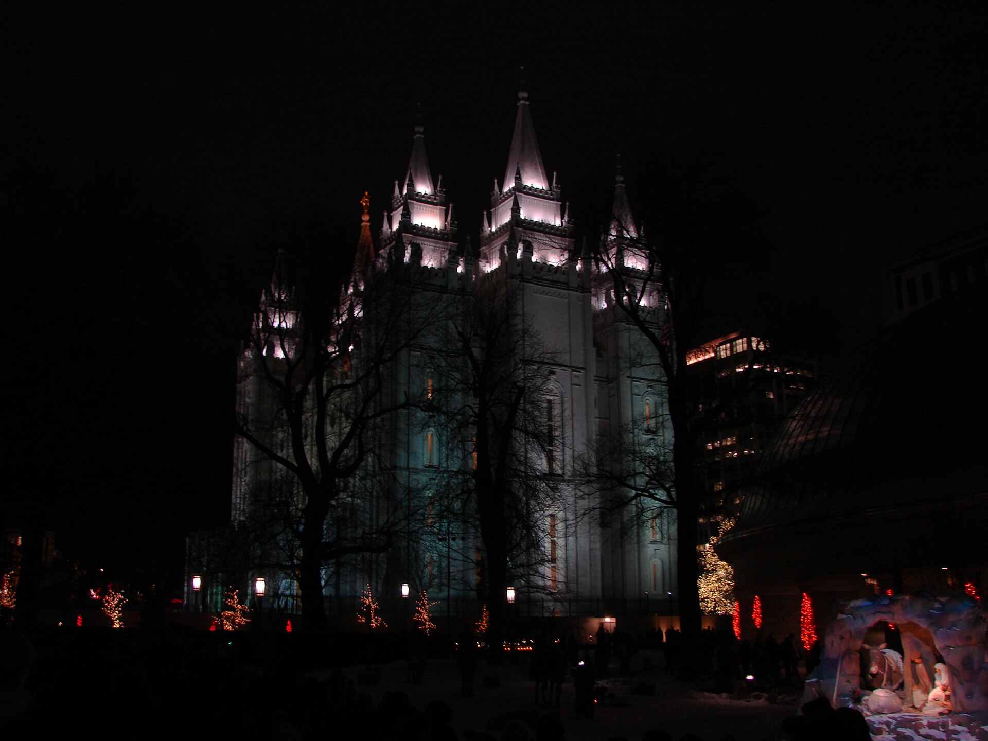 The Salt Lake Temple lit up at night surrounded by Christmas lights